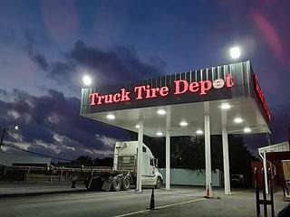 Truck Tire Depot sign illuminated at dusk, showcasing a tire service location for trucks, emphasizing accessibility and expertise in tire maintenance.
